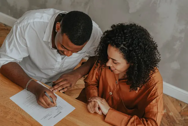 Couple signing documents at their kitchen table