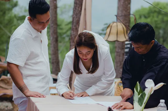 A bride signing a document with two people beside her